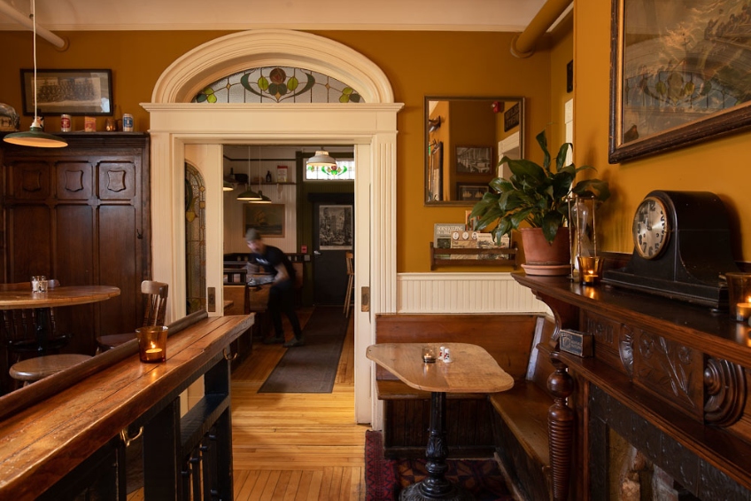Inside The Narrows Public House in Halifax, Nova Scotia, with restored wood finishes and furnishings, and an arched doorway.