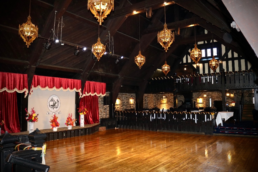 One of the event spaces at Toronto's Old Mill, with a Tudor revival-style design, a stage, banquet seating and vintage chandeliers.