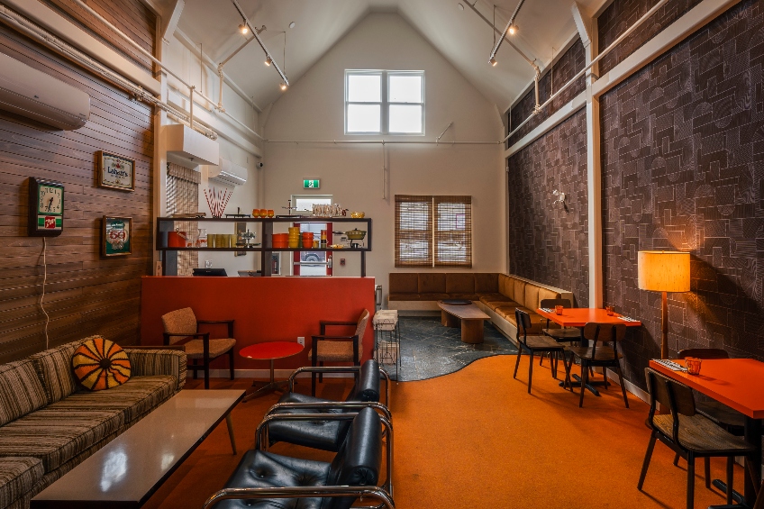 The upstairs at Vancouver, British Columbia's Mount Pleasant Vintage & Provisions, with a vaulted ceiling and 1970s-style furnishings in oranges and reds.