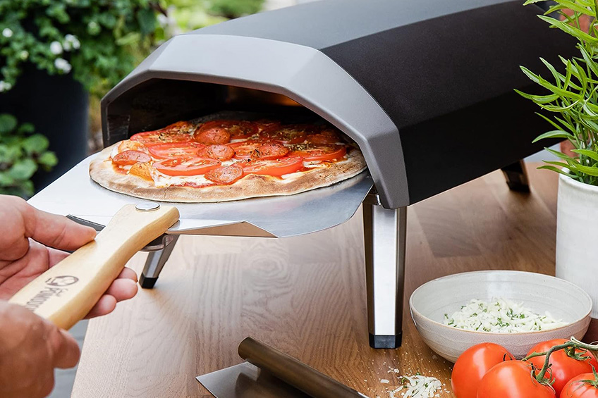 Chef Pomodoro aluminum metal pizza peel with pizza being loaded into a table top pizza oven.