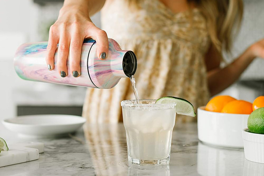 Woman pouring a cocktail out of a shaker.