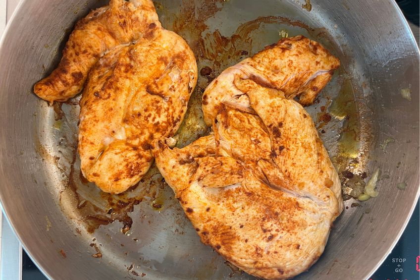 Two pan-fried chicken breasts in a pan