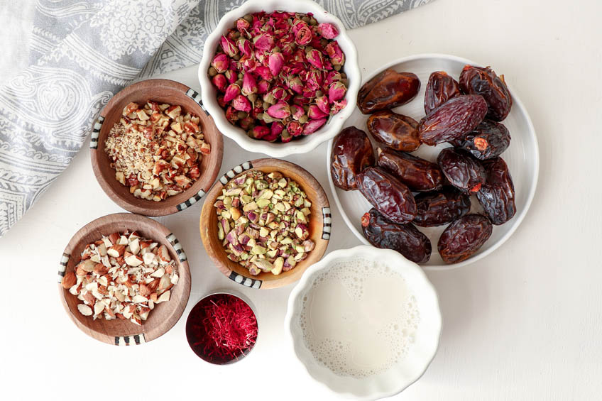 A flat lay of the ingredients to make ladoos: dates, nuts and rose petals