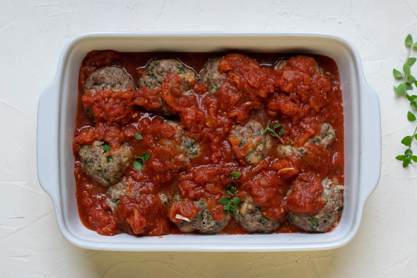Meatballs topped with sauce in a baking dish