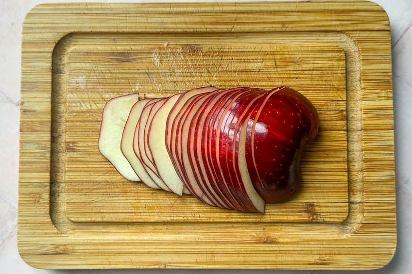 Thinly sliced apples on a cutting board