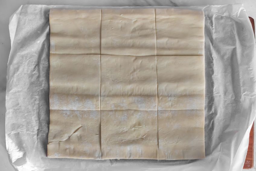 Sliced puff pastry on a sheet of parchment paper
