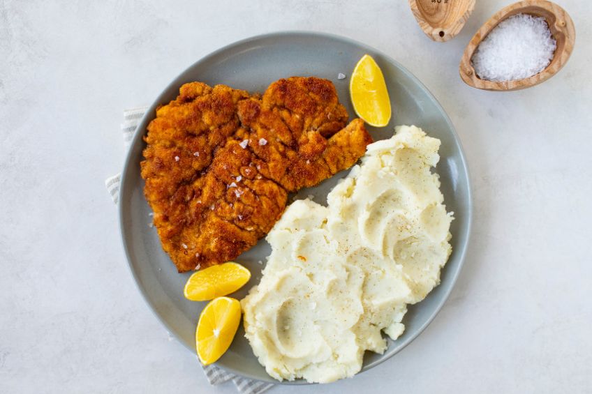 Chicken schnitzel on a plate with lemons and mashed potatoes