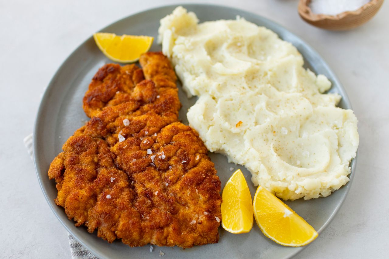 Chicken schnitzel on a plate with lemons and mashed potatoes