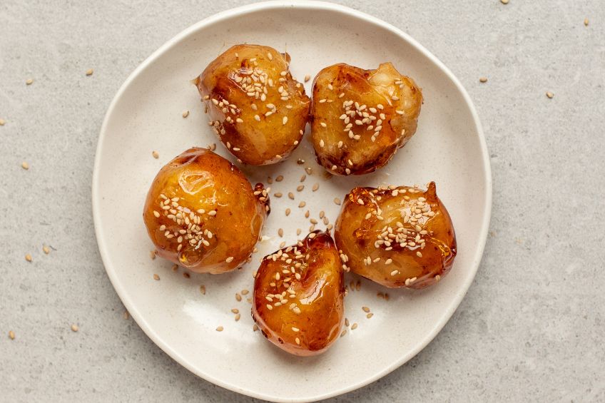 Toffee bananas on a plate, topped with sesame seeds