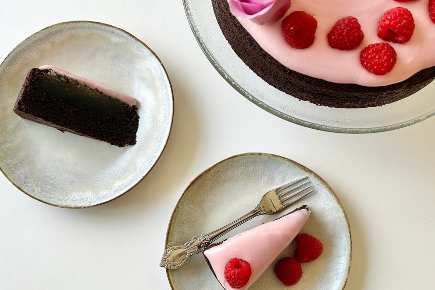 Two slices of One-Bowl Chocolate Cake With Pink Raspberry Cream Cheese Frosting on plates