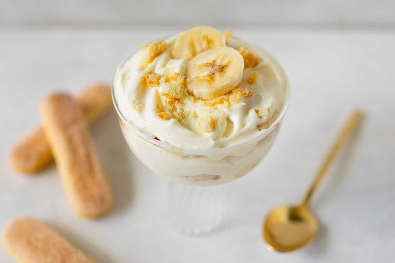 Banana pudding in a glass bowl with a spoon and lady fingers