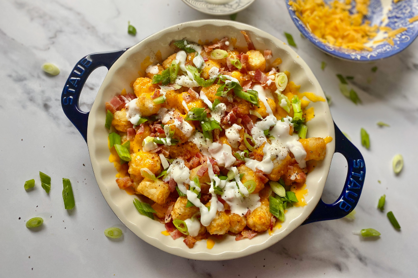 Loaded baked potato cheesy tots in a pie dish, ready to serve