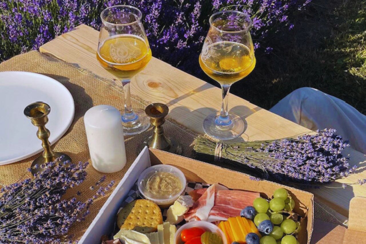 Charcuterie board, lavender and two wine glasses on a picnic table