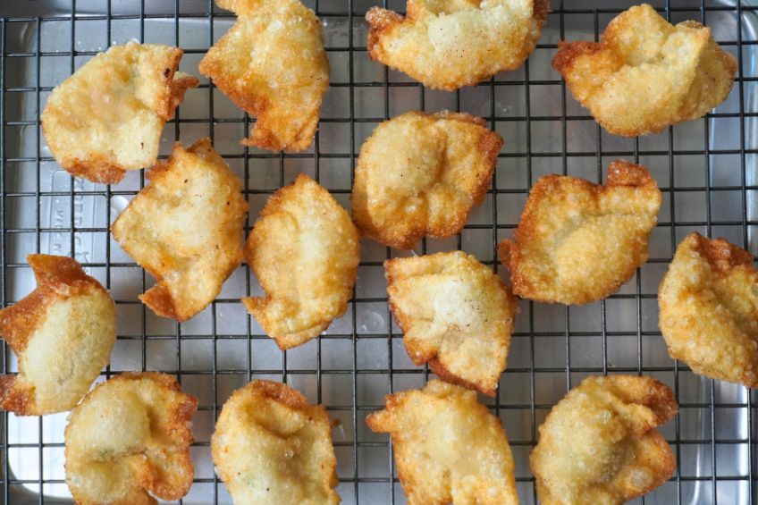 golden fried shrimp dumplings on a wire rack after being fried