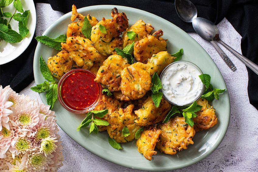 zucchini fritters arranged on a plate with harrisa honey and mint yogurt dip