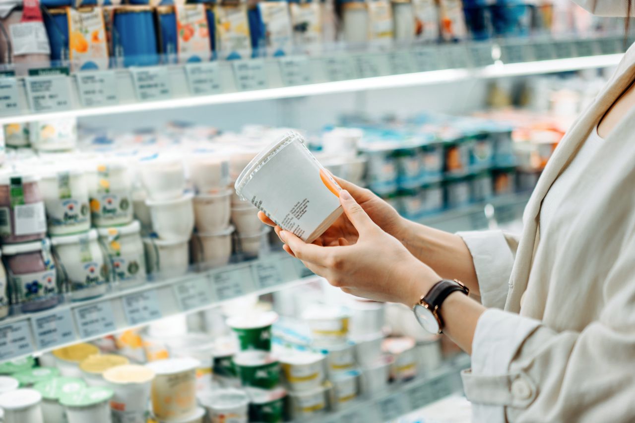 Female holding a cup of greek yogurt in the dairy section