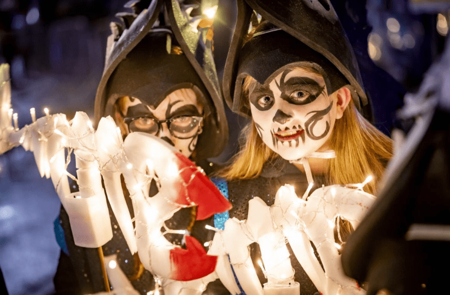 Two kids dressed in Halloween costumes with face paint.