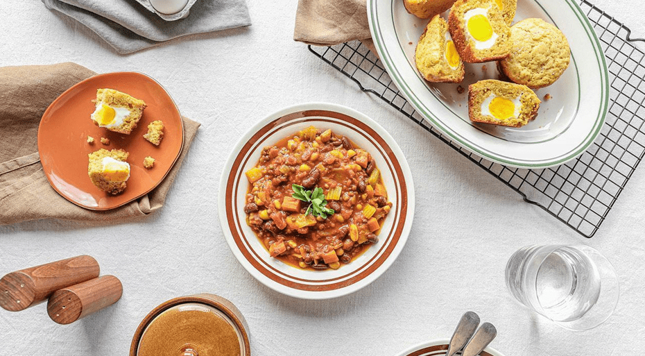 a bowl of chili with egg muffins cut open beside it